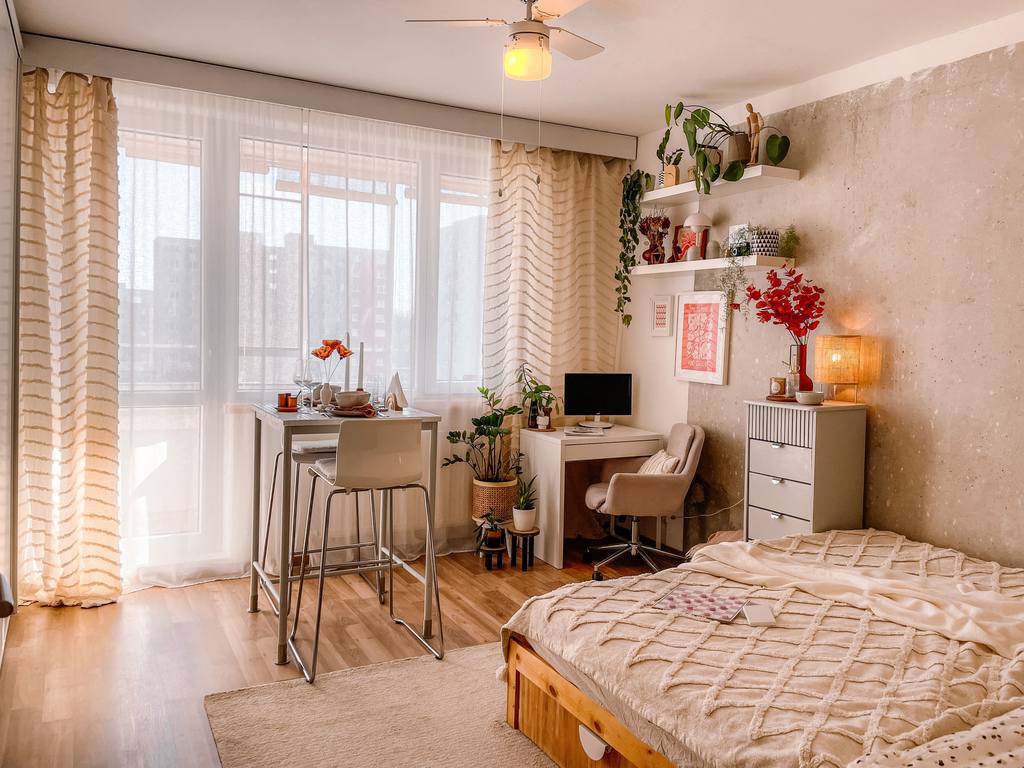 Guest bedroom with a bed, compact desk, storage cabinet, and small dining table in a multipurpose space.