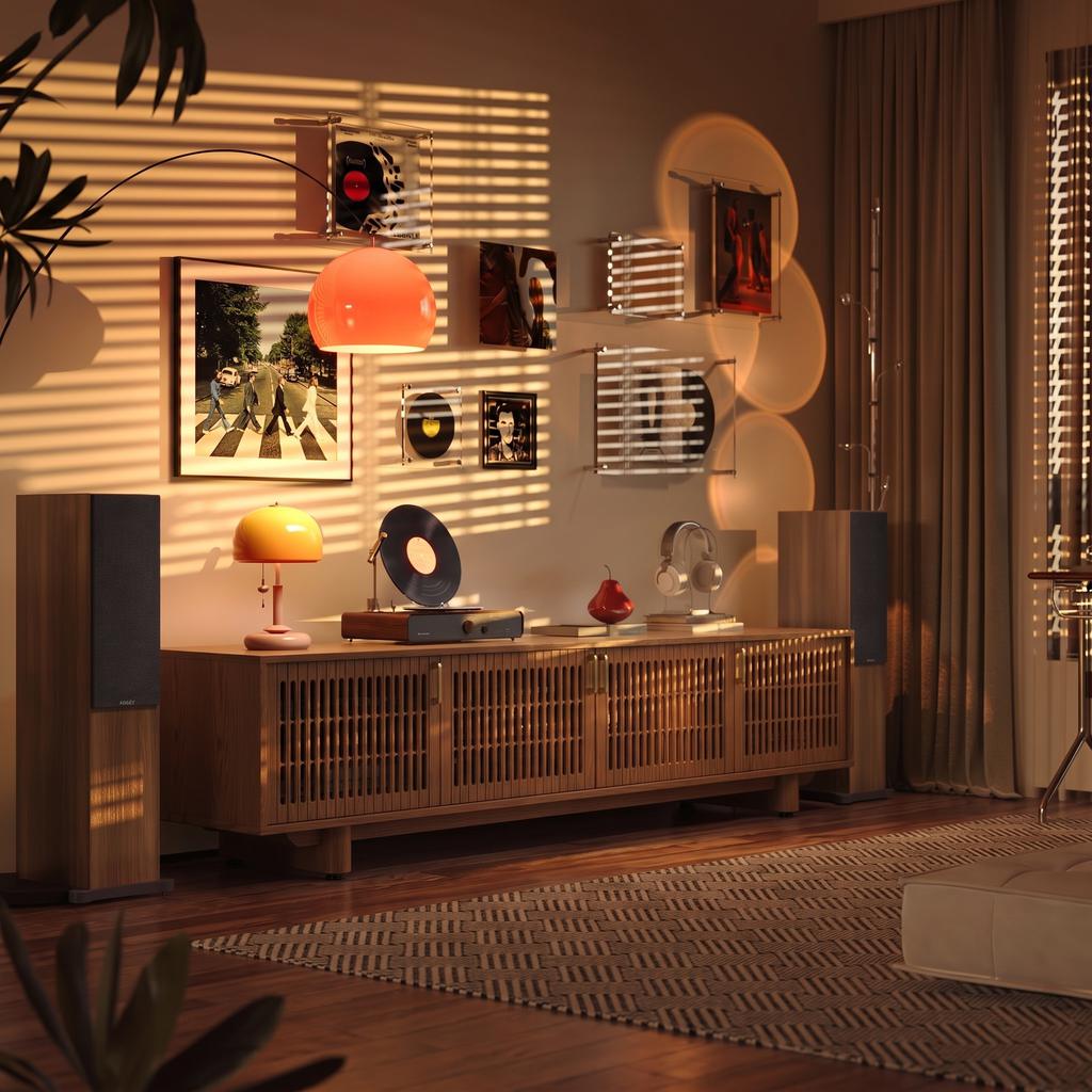 Warm, vintage-inspired music listening room with a wooden media console, turntable, vinyl record wall display, floor speakers, and soft sunset lighting.