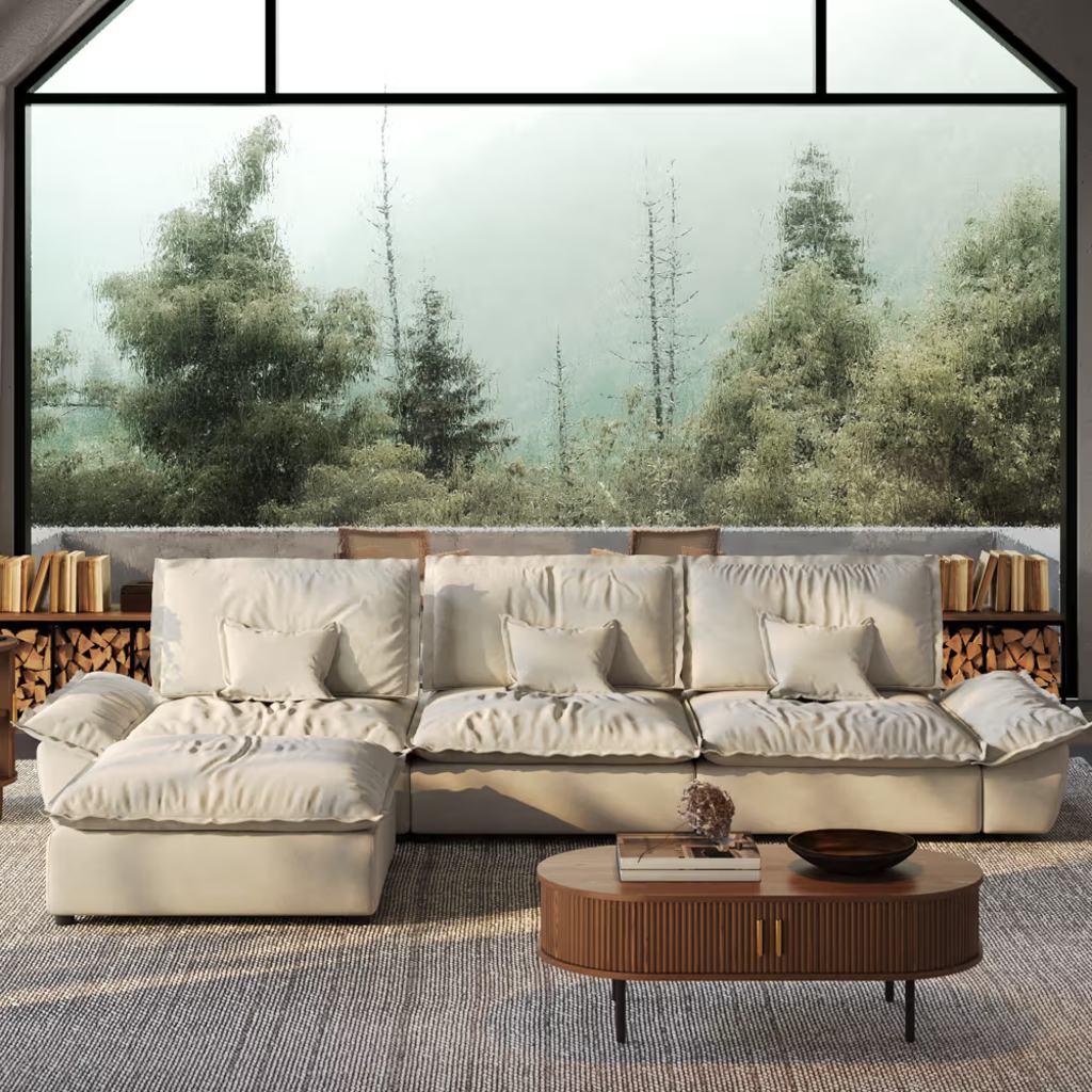 Cream L-shaped sectional sofa with a chaise lounge and plush cushions in a modern living room with a wooden coffee table and floor-to-ceiling windows.