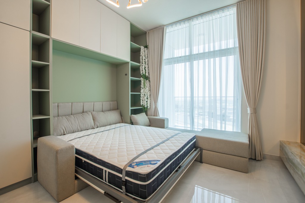 Space-saving Murphy bed with a pull-down mattress, built-in cabinets, and a window-side bench in a bright, modern guest room.