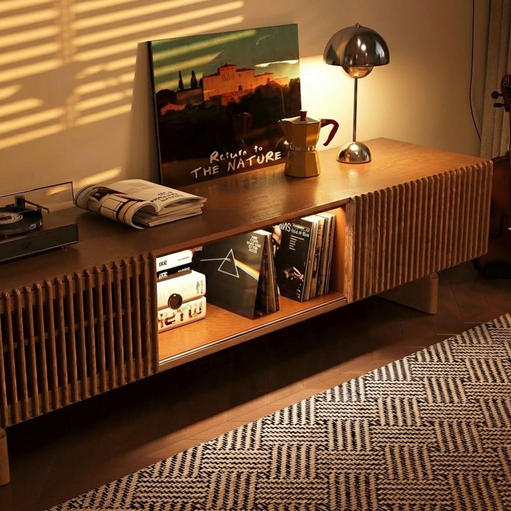 Mid-century modern living room with a fluted wood TV console, open shelf storage, warm lighting, books, and a patterned rug.