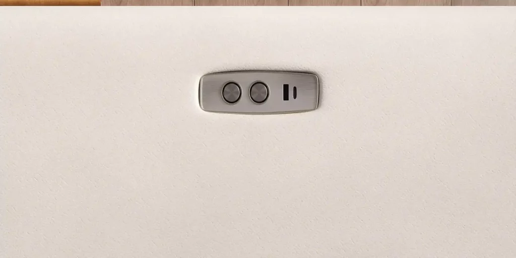 Close-up of a power sofa control panel with two adjustment buttons on a light-colored upholstered surface.
